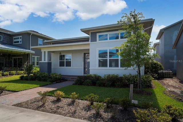 view of front of home featuring a front lawn, covered porch, and central air condition unit