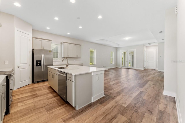 kitchen featuring appliances with stainless steel finishes, a kitchen island with sink, sink, and light hardwood / wood-style flooring