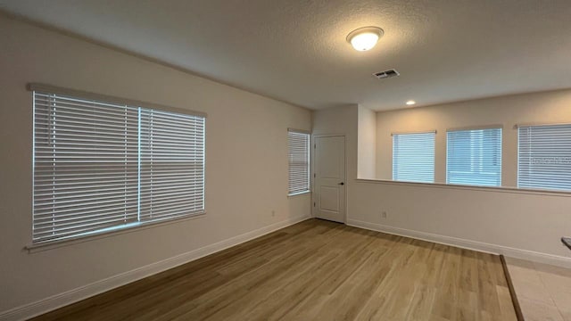 spare room with a textured ceiling and hardwood / wood-style flooring