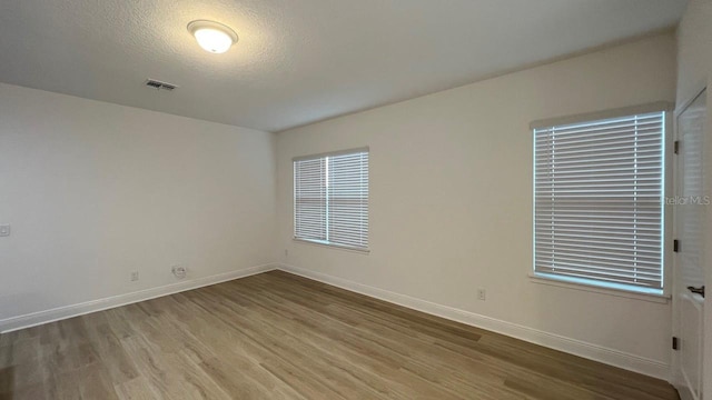 unfurnished room with wood-type flooring and a textured ceiling