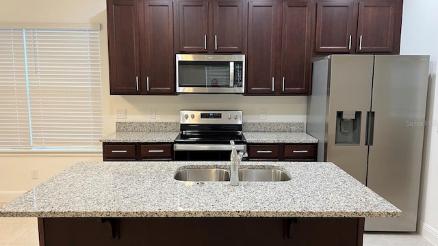 kitchen featuring light stone countertops, a breakfast bar area, sink, and stainless steel appliances