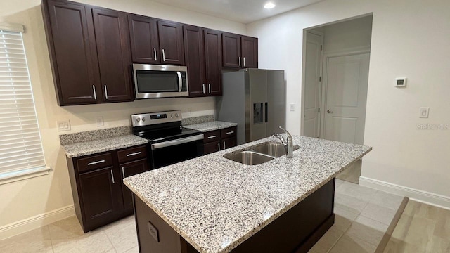 kitchen featuring dark brown cabinetry, an island with sink, appliances with stainless steel finishes, and sink