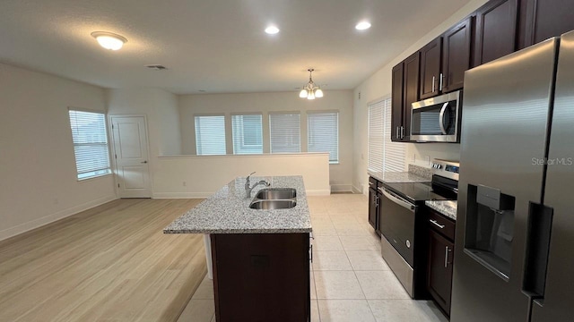 kitchen featuring sink, dark brown cabinets, a center island with sink, stainless steel appliances, and light wood-type flooring