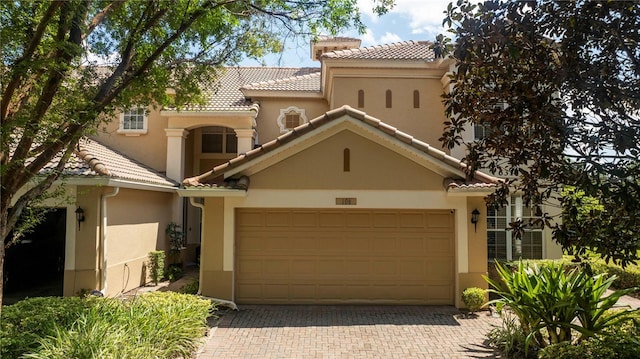 mediterranean / spanish home with decorative driveway, a garage, a tile roof, and stucco siding