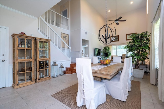 dining area with high vaulted ceiling, ceiling fan with notable chandelier, light tile patterned floors, and crown molding