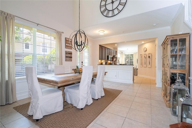 tiled dining area featuring a high ceiling, ornamental molding, and an inviting chandelier