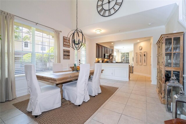 dining room with crown molding, a notable chandelier, and light tile patterned floors