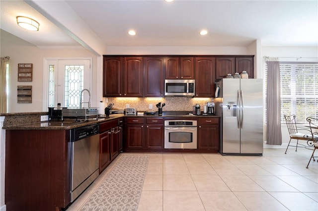 kitchen with dark stone countertops, sink, stainless steel appliances, and plenty of natural light