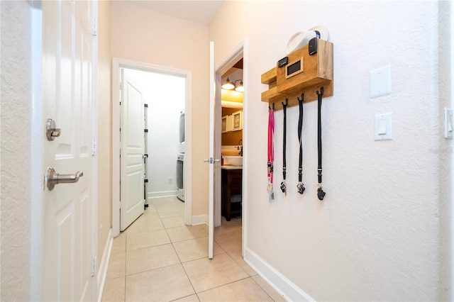 hallway featuring light tile patterned flooring and stacked washer and clothes dryer