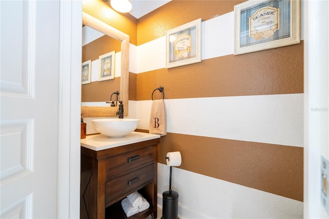 half bath featuring vanity and a textured wall