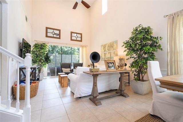 tiled living room with ceiling fan and a high ceiling