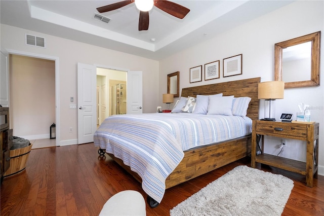 bedroom featuring a raised ceiling, dark hardwood / wood-style floors, and ceiling fan