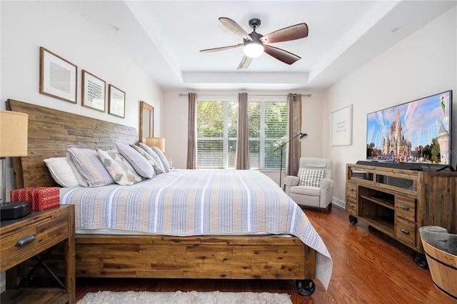 bedroom with ceiling fan, a raised ceiling, and dark hardwood / wood-style floors