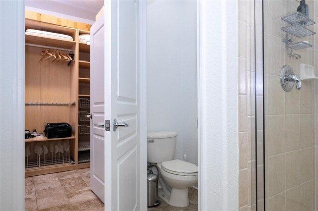 bathroom featuring a stall shower, toilet, and a spacious closet