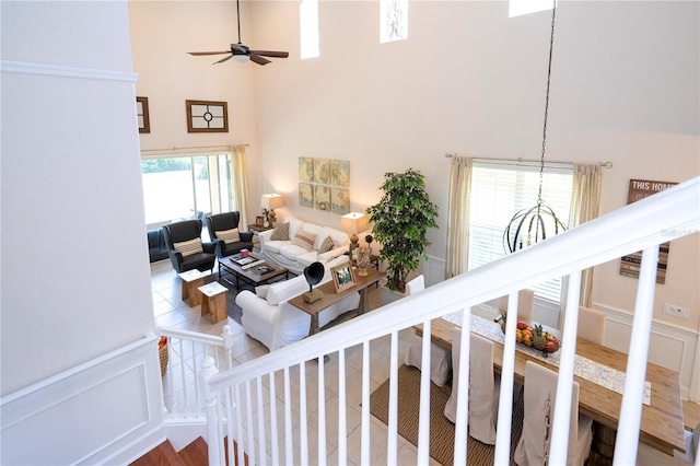 living room featuring ceiling fan, a towering ceiling, wood-type flooring, and a healthy amount of sunlight