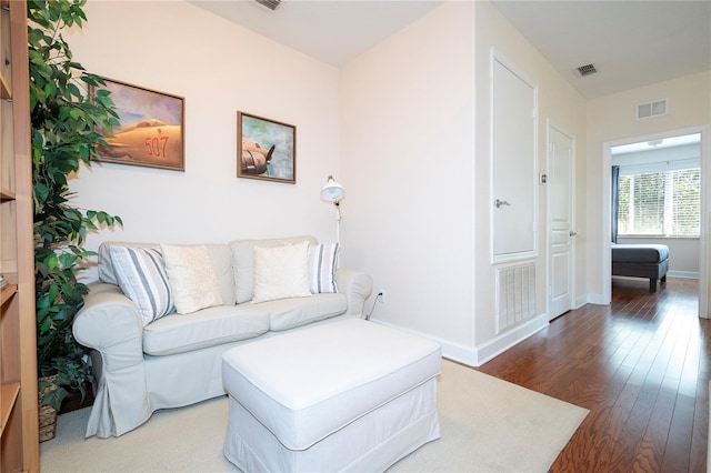 living area with baseboards, visible vents, and wood finished floors