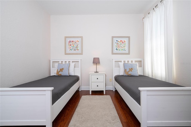 bedroom with multiple windows and dark hardwood / wood-style flooring