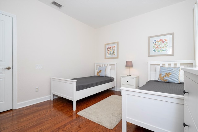 bedroom featuring baseboards, visible vents, and wood finished floors