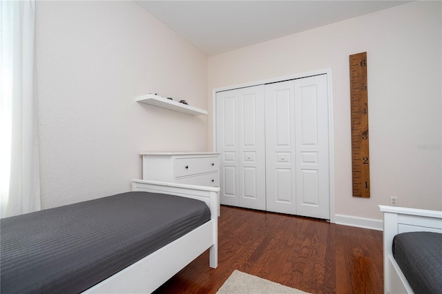 bedroom with baseboards, a closet, and dark wood finished floors