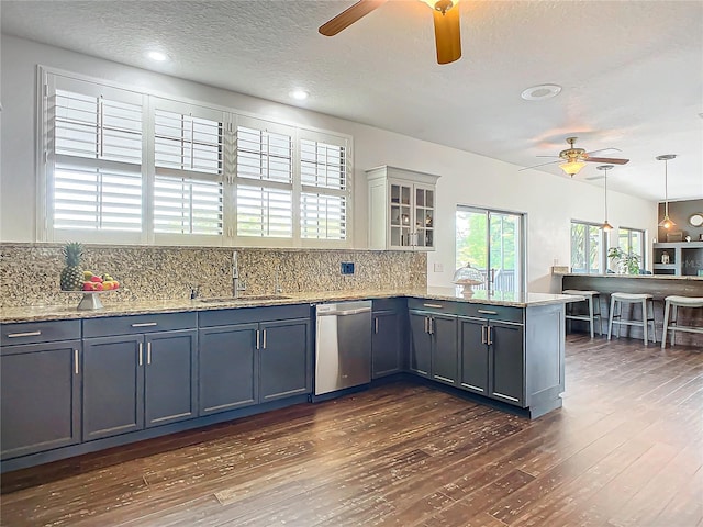 kitchen with kitchen peninsula, backsplash, sink, pendant lighting, and dishwasher