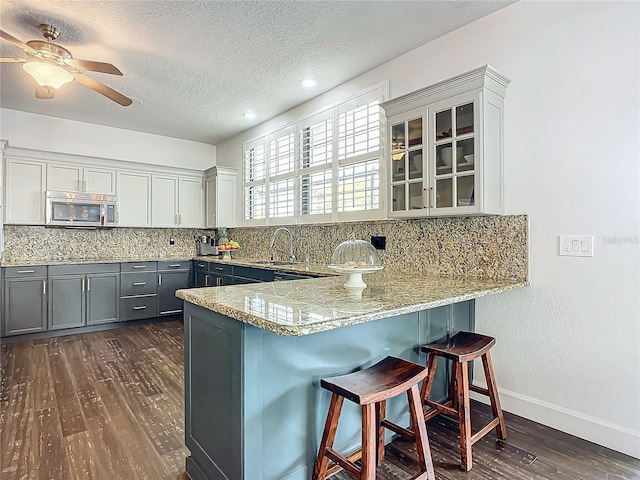 kitchen with gray cabinetry, sink, ceiling fan, dark hardwood / wood-style floors, and kitchen peninsula