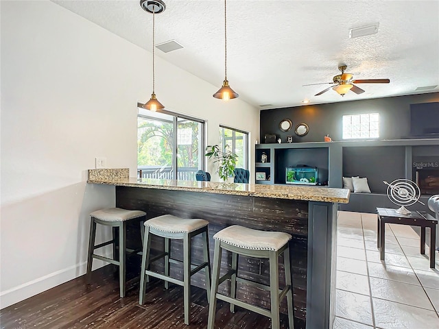 kitchen with kitchen peninsula, a kitchen breakfast bar, a textured ceiling, and pendant lighting