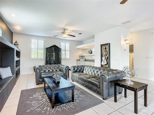 living room with ceiling fan, light tile patterned floors, and a textured ceiling