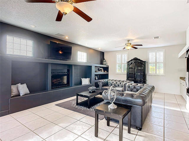 living room featuring a fireplace, light tile patterned floors, and a textured ceiling