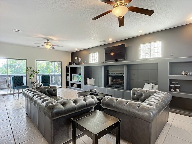 living room with a tile fireplace, light tile patterned floors, and a textured ceiling