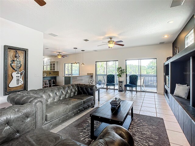 living room featuring light tile patterned floors, a textured ceiling, and ceiling fan