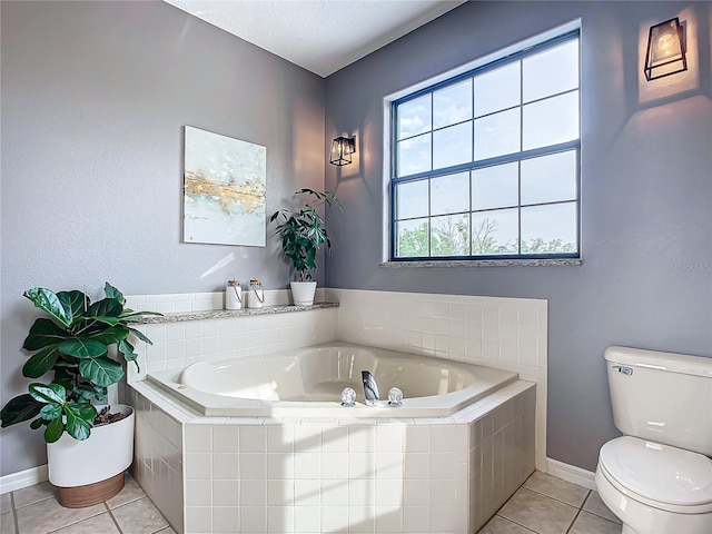 bathroom with tile patterned floors, a relaxing tiled tub, and toilet