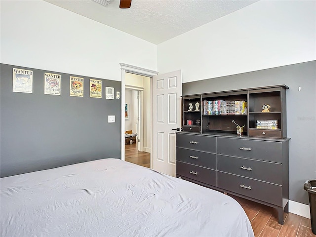 bedroom featuring a textured ceiling, ceiling fan, and dark hardwood / wood-style floors