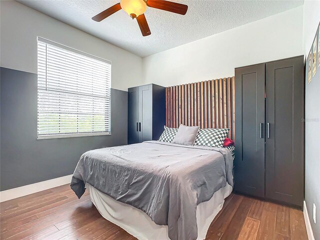 bedroom featuring a textured ceiling, ceiling fan, and dark hardwood / wood-style floors