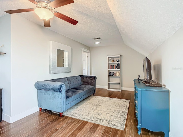 living room with ceiling fan, lofted ceiling, a textured ceiling, and dark wood-type flooring