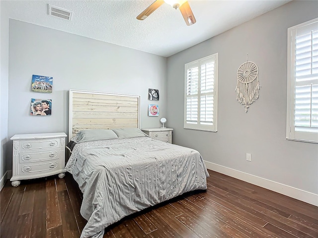 bedroom featuring ceiling fan, dark hardwood / wood-style floors, and a textured ceiling