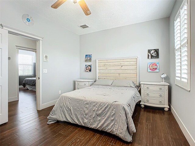 bedroom featuring a textured ceiling, ceiling fan, and dark wood-type flooring