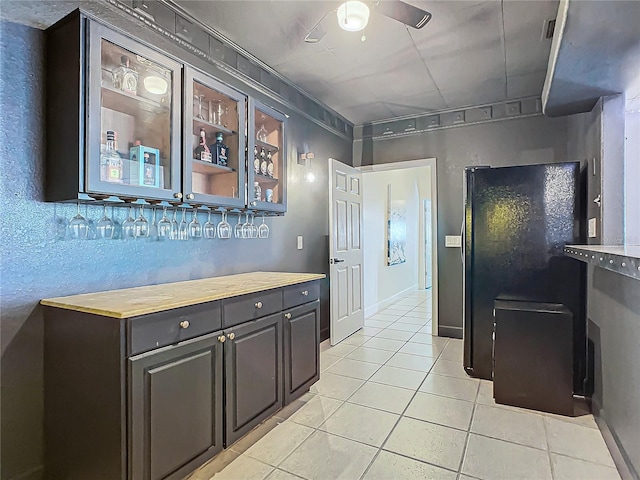 kitchen with wood counters, ceiling fan, dark brown cabinetry, and light tile patterned floors