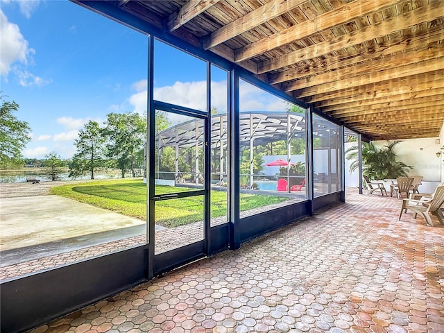 unfurnished sunroom featuring beamed ceiling and a water view