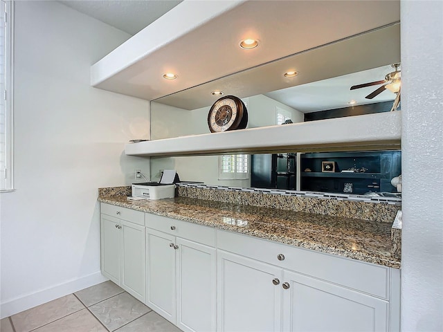 kitchen with white cabinets, ceiling fan, dark stone countertops, and light tile patterned floors