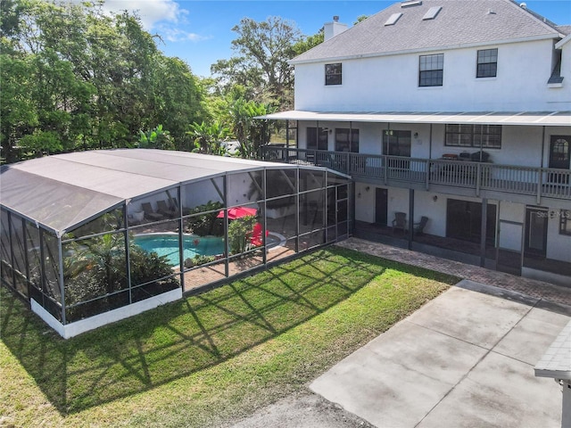 view of swimming pool with a lawn, glass enclosure, and a patio area