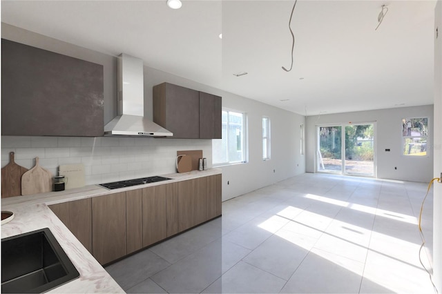 kitchen featuring decorative backsplash, light tile patterned flooring, cooktop, and wall chimney range hood