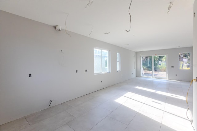 empty room with a healthy amount of sunlight and light tile patterned floors