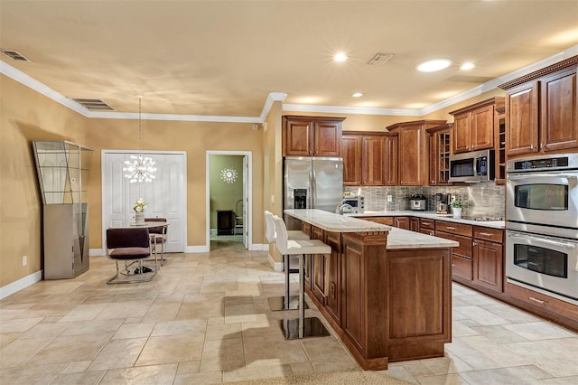 kitchen with a center island, decorative light fixtures, a kitchen bar, stainless steel appliances, and a chandelier