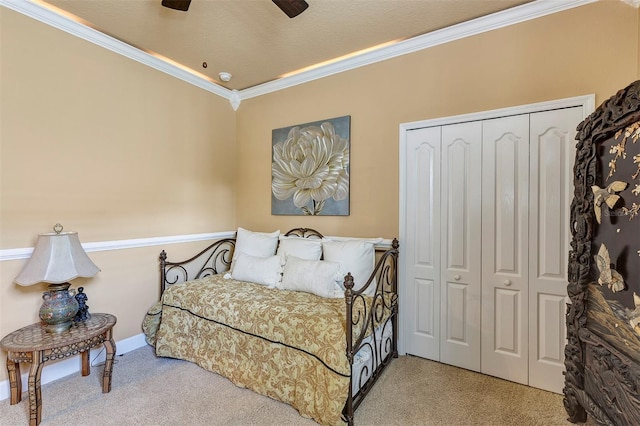 carpeted bedroom with ceiling fan, a closet, and crown molding