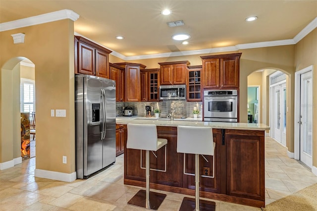 kitchen with sink, decorative backsplash, a kitchen island, a kitchen bar, and stainless steel appliances