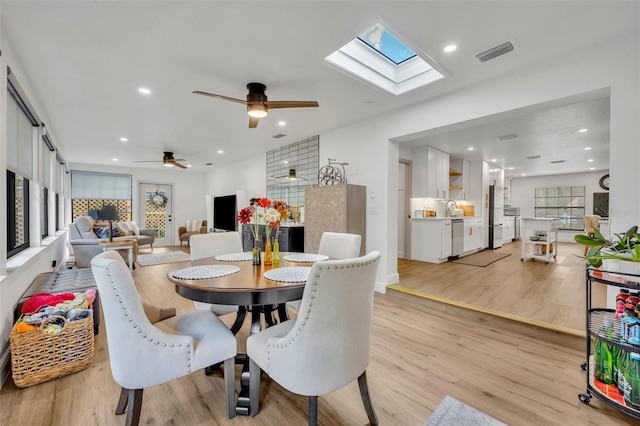 dining space featuring a skylight, ceiling fan, and light hardwood / wood-style floors