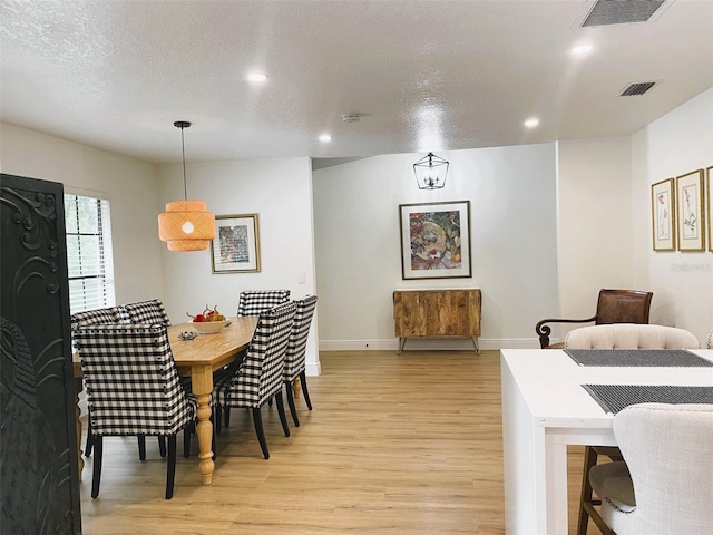 dining area featuring light hardwood / wood-style floors and a textured ceiling