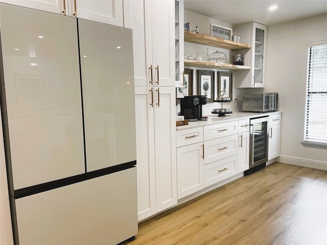 kitchen featuring white cabinets, light hardwood / wood-style floors, stainless steel appliances, and beverage cooler