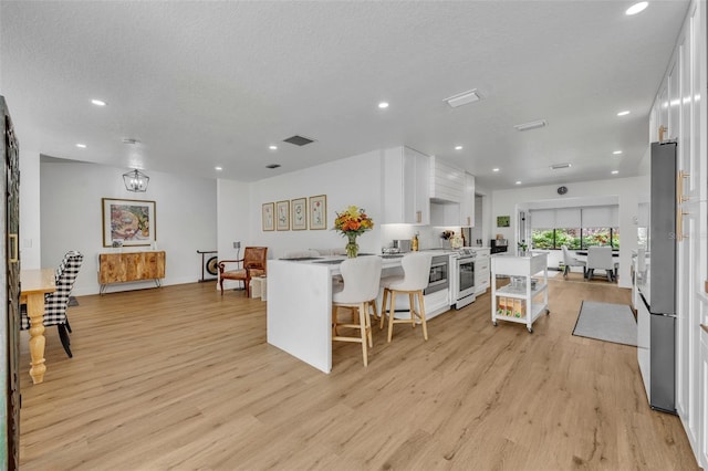 kitchen featuring kitchen peninsula, a kitchen breakfast bar, light hardwood / wood-style flooring, and white cabinetry