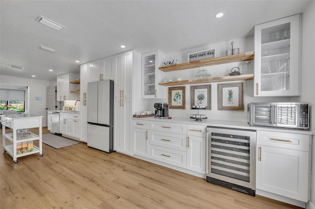 kitchen with white appliances, white cabinetry, and wine cooler